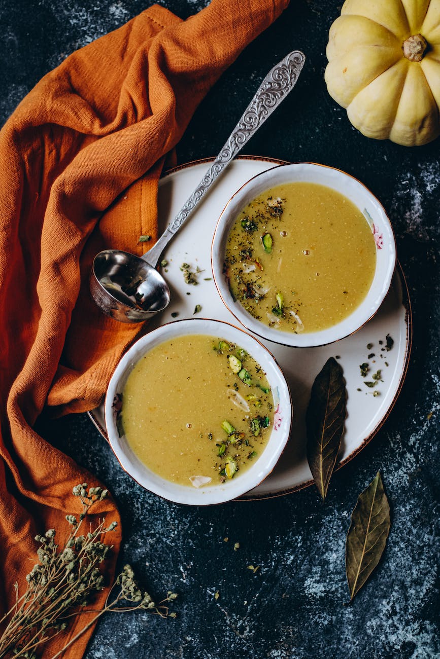 two pumpkin soups served with herbs and pistachio