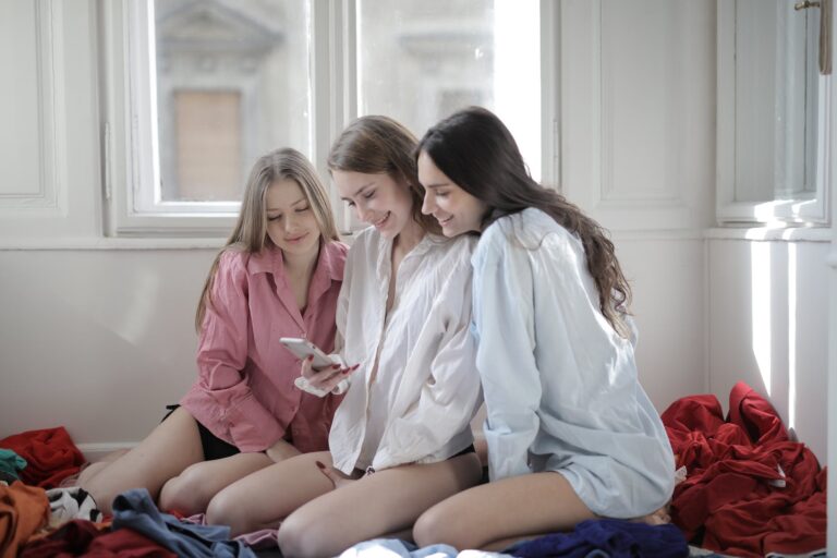 group of young women browsing smartphone together in messy room