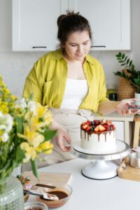 smiling woman decorating cake with berries