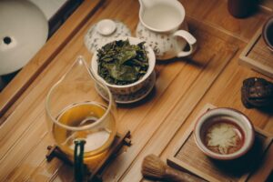 white ceramic teapot beside cup with leaves