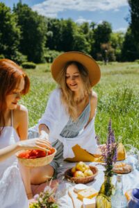 women sitting on a picnic blanket while eating